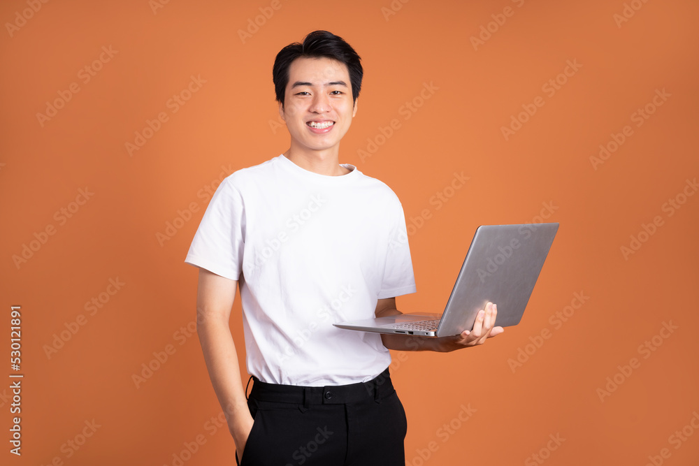 asian man holding laptop, isolated on orange background asian man holding laptop, isolated on orange background