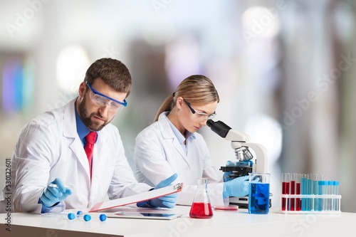 Scientists with microscopes doing research and working in laboratory