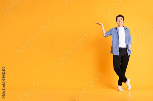 full body image of asian man posing on yellow background © 1112000