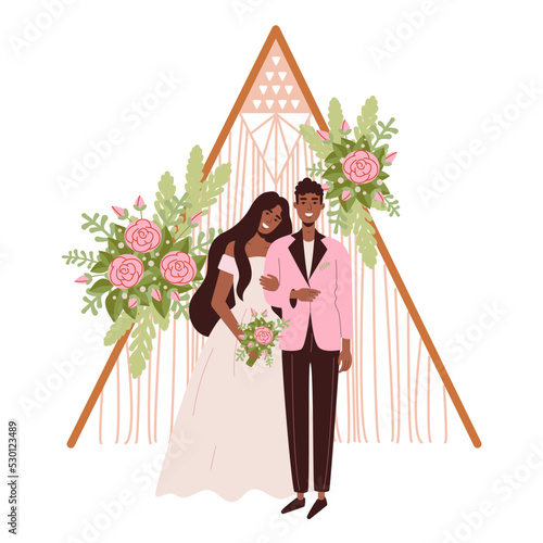 Wedding arch in Hippie and Boho style. Beautiful dark-skinned bride and groom. A woman in a wedding dress with a bouquet