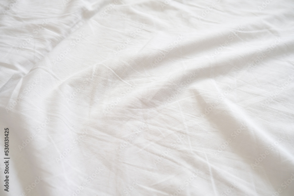 Top view of wrinkles on an untidy white bed sheet, linen in a bedroom after a long night sleep and waking up in the morning
