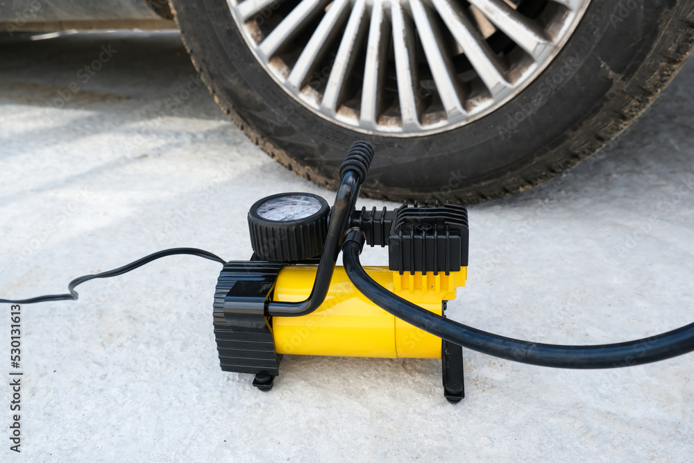 Inflating a flat tire, wheel with an electric pump on a road, maintenance and car service
