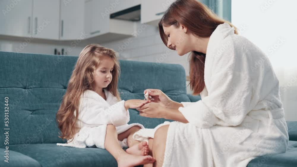 A young woman paints her little daughter's nails at home. A young woman paints her little daughter's nails at home.