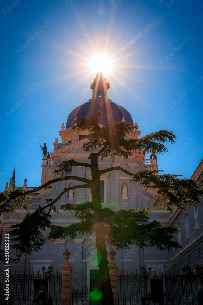 Φωτογραφία Sun setting in a sun burst behind the cross of the Cathedral of Our Lady of La Almudena in Madrid, Spain, consecrated by Pope John Paul II in 1993