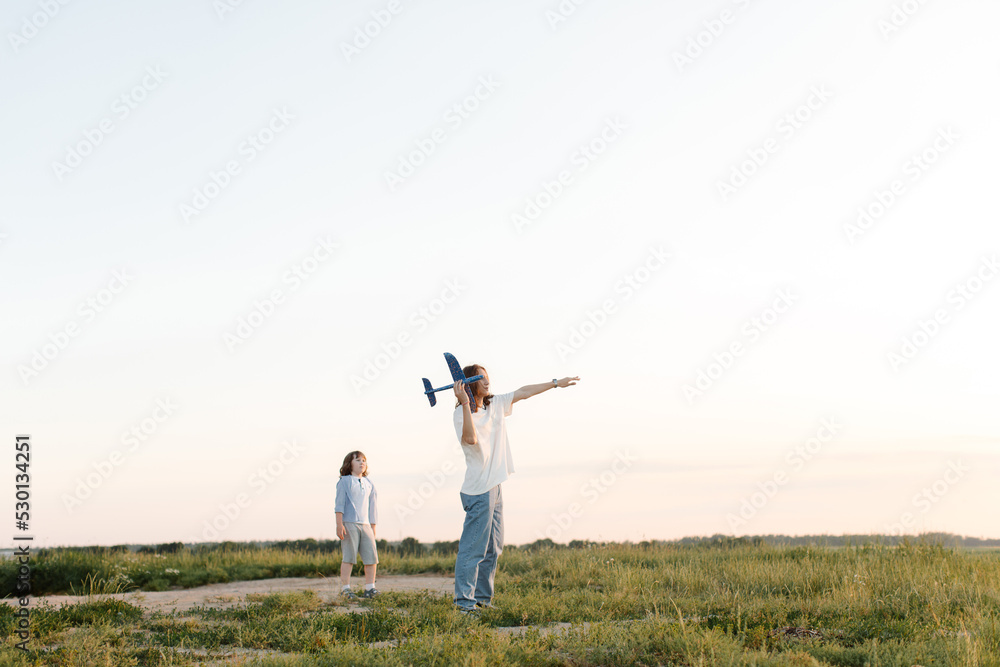 Boys, children run through wheat field play with toy airplane in hand, dream of flying. Child plays with his toy with an plane. Elder and younger brothers. High quality photo