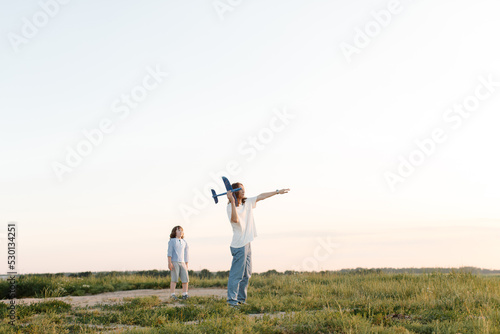 Boys, children run through wheat field play with toy airplane in hand, dream of flying. Child plays with his toy with an plane. Elder and younger brothers. High quality photo