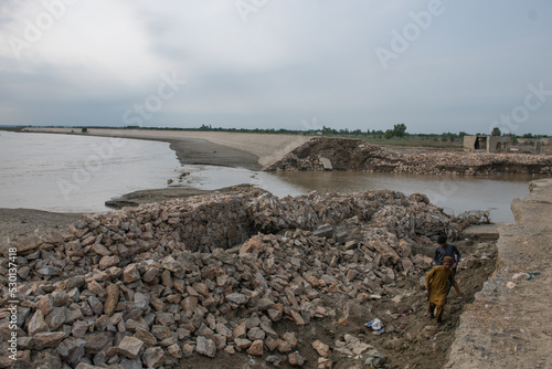 Children walk around pile of ruins that once were their homes but floods have destroyed everything 