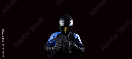 Fototapeta Naklejka Na Ścianę i Meble -  man in a motorcycle helmet in an outfit on a dark studio background.