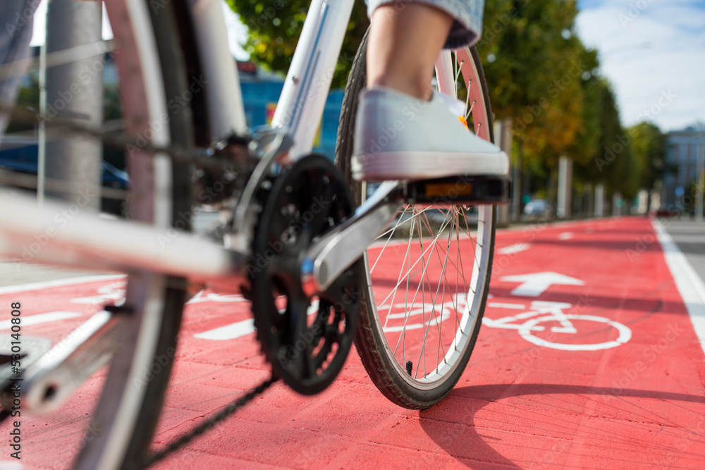 Fototapeta premium traffic, city transport and people concept - close up of woman cycling along red bike lane with signs of bicycles and two way arrows on street