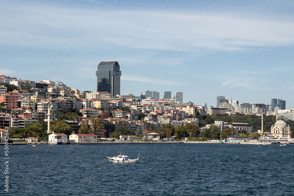 View of a small fishing boat on Bosphorus and Gunussuyu area of Beyoglu district in Istanbul. It is a sunny summer day.