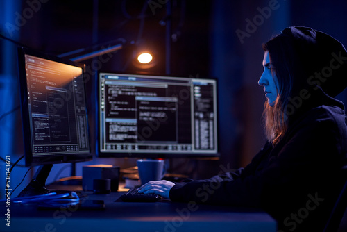 Fototapeta cybercrime, hacking and technology concept - female hacker in dark room writing