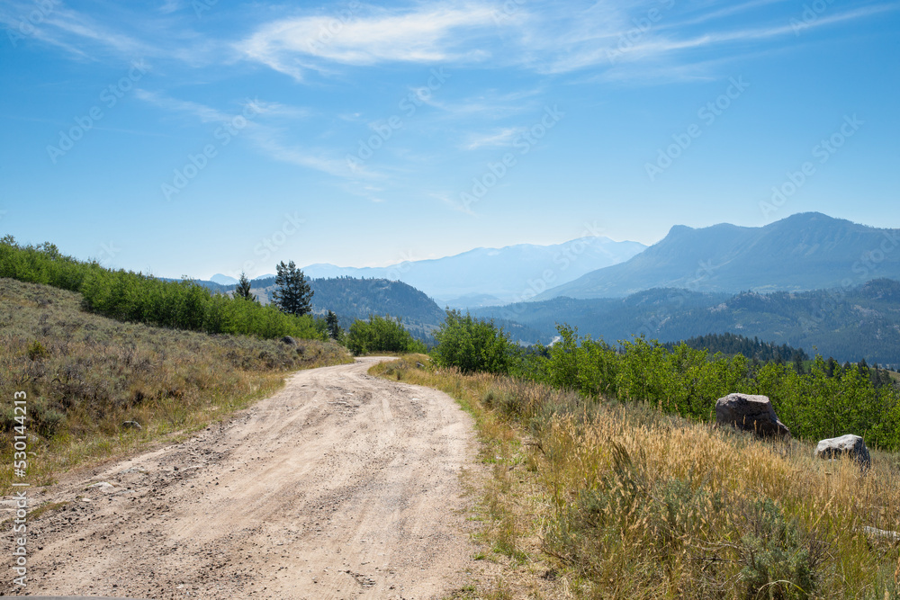 Autumn morning on a bad rural back country dirt road in the mountains on the way to camping with wildfire smoke haze in the distance