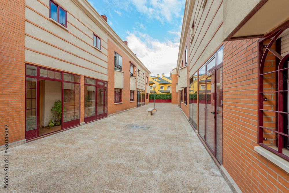 passageway between single-family urban residential homes with red aluminum carpentry