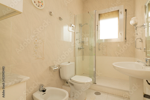 toilet in white tones with square aluminum window, mirror on the wall and shower cabin with glass partition