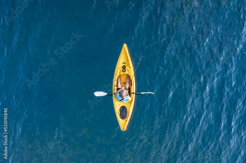 Yellow kayak overhead aerial on a blue water lake with man fishing