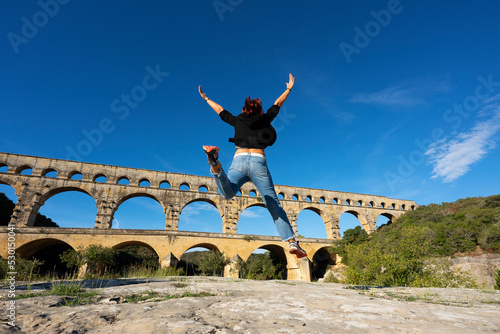 View of Woman jumping in front of Pont du Gard photo