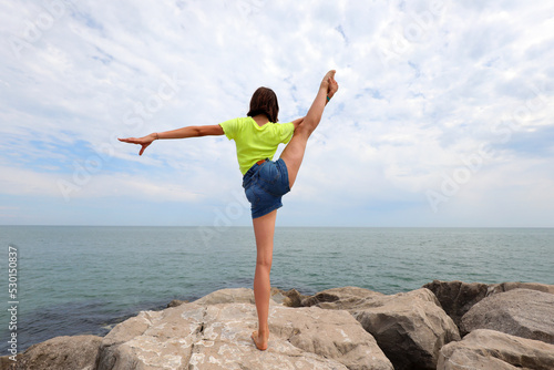 Photos girl doing exercises on the rocks to keep fit in the summer
