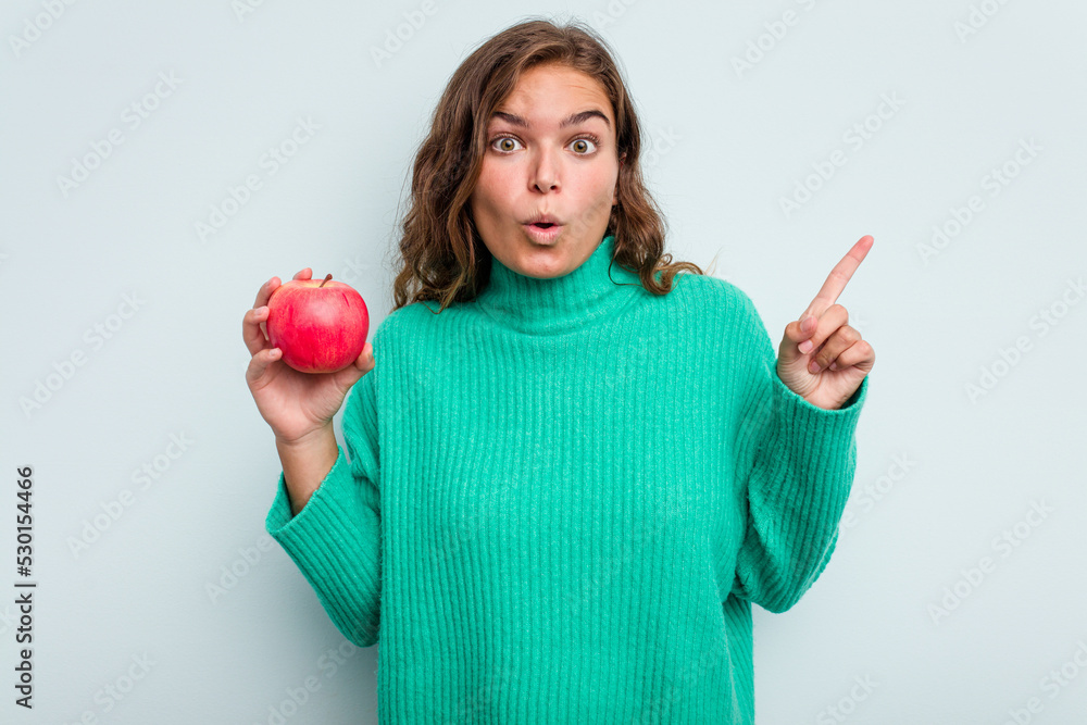 Young caucasian woman with an apple isolated on blue background having some great idea, concept of creativity. Young caucasian woman with an apple isolated on blue background having some great idea, concept of creativity.