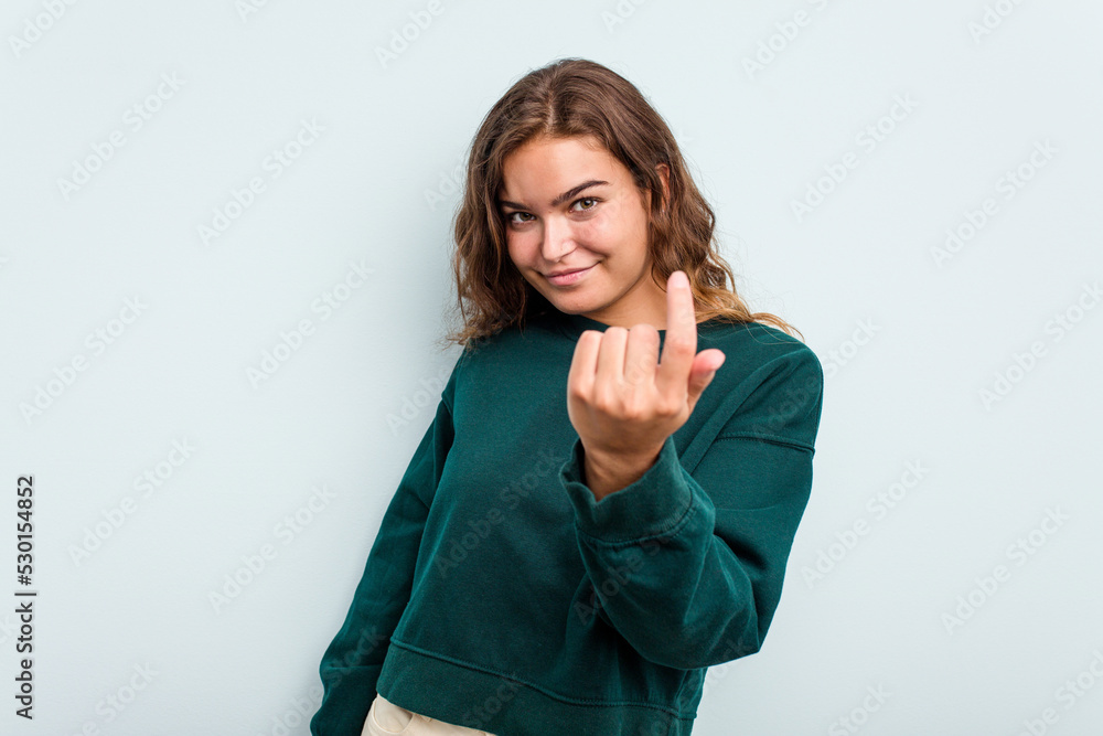 Young caucasian woman isolated on blue background pointing with finger at you as if inviting come closer. Young caucasian woman isolated on blue background pointing with finger at you as if inviting come closer.