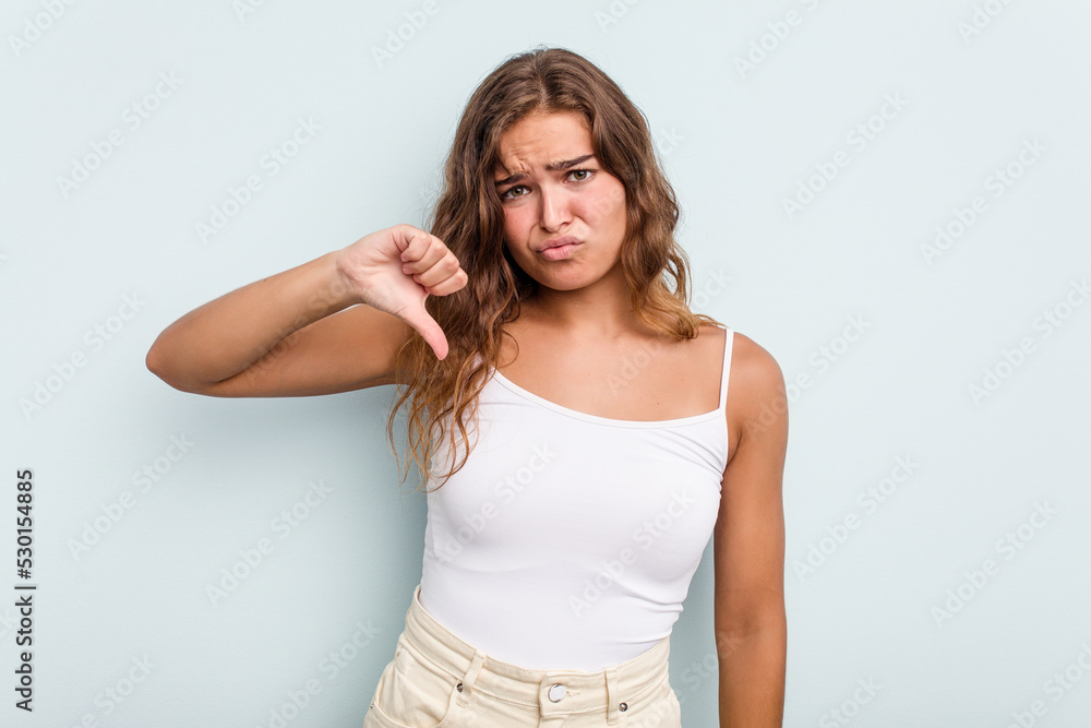 Young caucasian woman isolated on blue background showing thumb down, disappointment concept. Young caucasian woman isolated on blue background showing thumb down, disappointment concept.