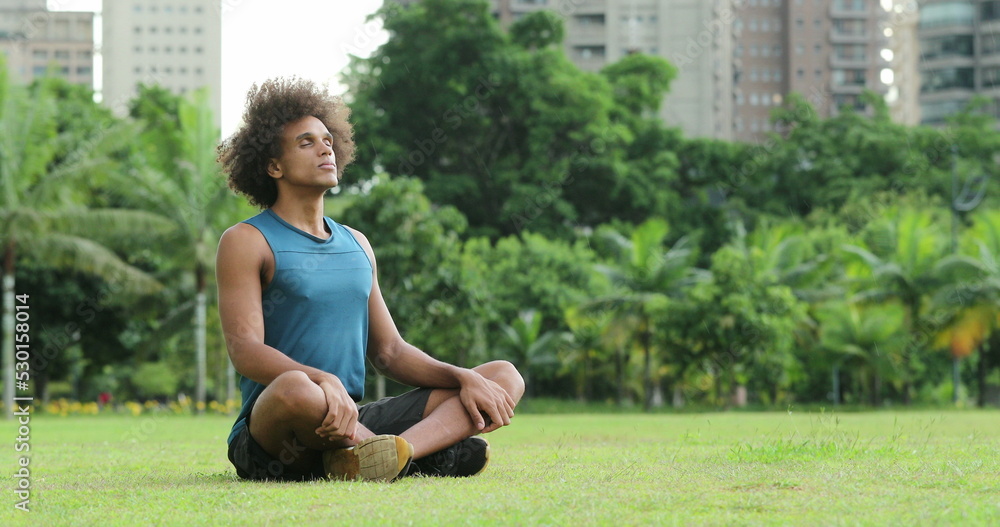 Young african black man seated on grass in meditation and contemplation