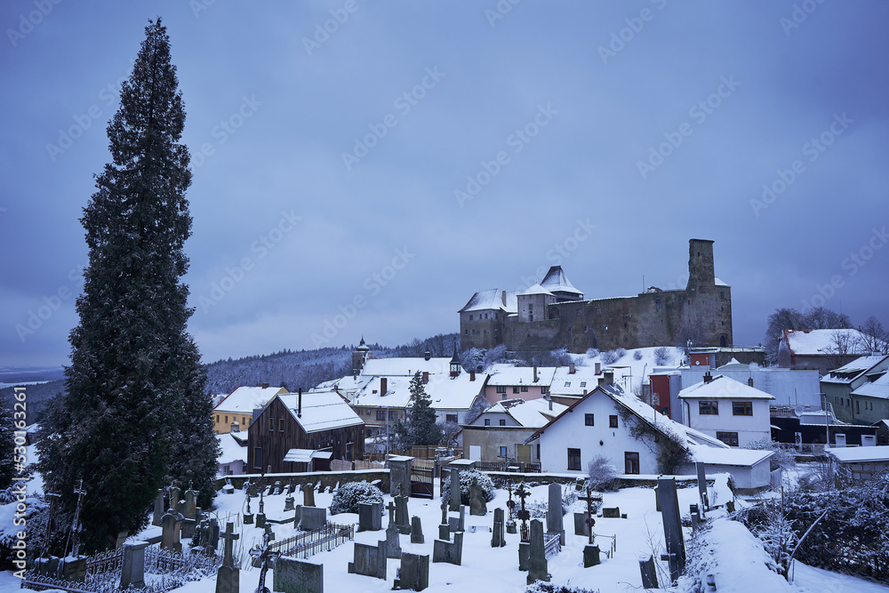 Obraz premium Lipnice nad Sázavou, one of the largest castles in Czech republic, build in gothic style architecture with small pitoresque city under the castle. Picture is taken from cemetery in cold winter sunset.