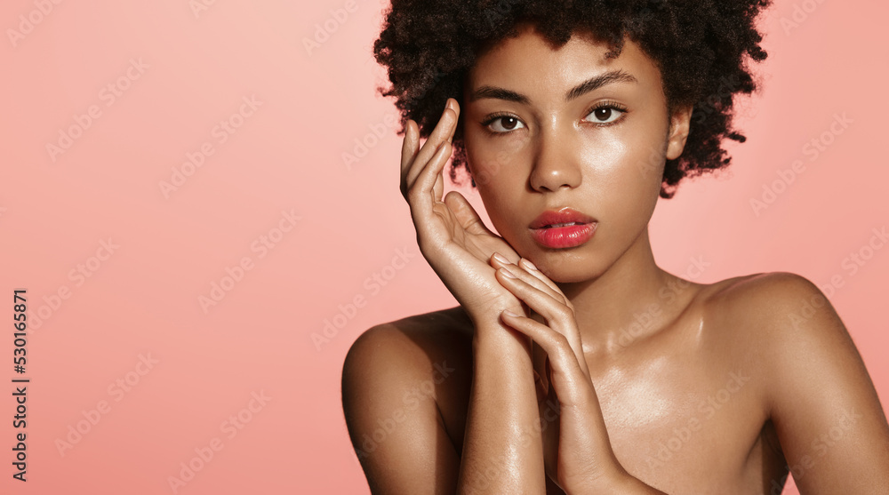 Beauty face. Vertical portrait of African American woman with nude natural makeup, smiling romantic, standing naked to apply moisturizer, facial toners, getting ready for romantic date, pink Beauty face. Vertical portrait of African American woman with nude natural makeup, smiling romantic, standing naked to apply moisturizer, facial toners, getting ready for romantic date, pink