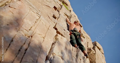 Up angle of rock climber standing on rock wall