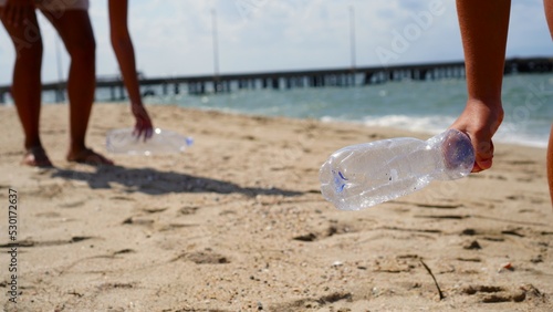 Woman and girl collect plastic waste on the sea shores in Sardinia with the help of garbage bags and gloves, doing volunteer work to combat plastic pollution