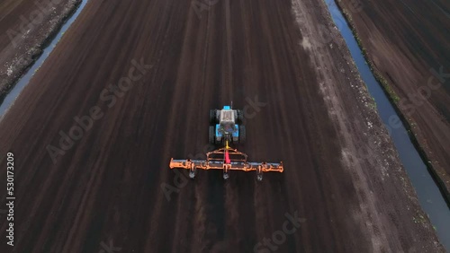 Peat Harvester Tractor on Collecting Extracting Peat. Mining and harvesting peatland. Area drained of the mire are used for peat extraction. Drainage and destruction of peat bogs.  photo