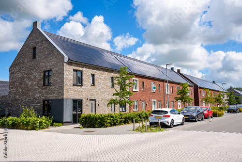 Row of new energy efficient brick terraced houses with the rooftop covered with solar panels on a sunny day