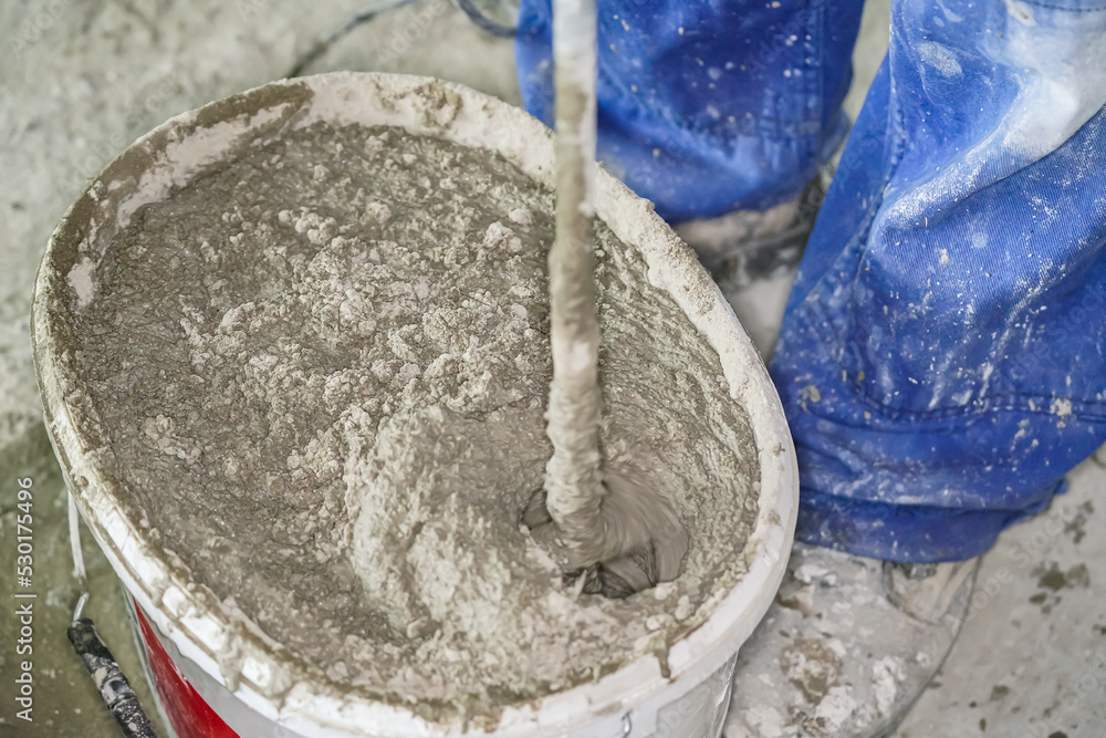 Fototapeta premium Mortar cement paste, mostly dry, mixed in bucket at house construction site, closeup detail from above