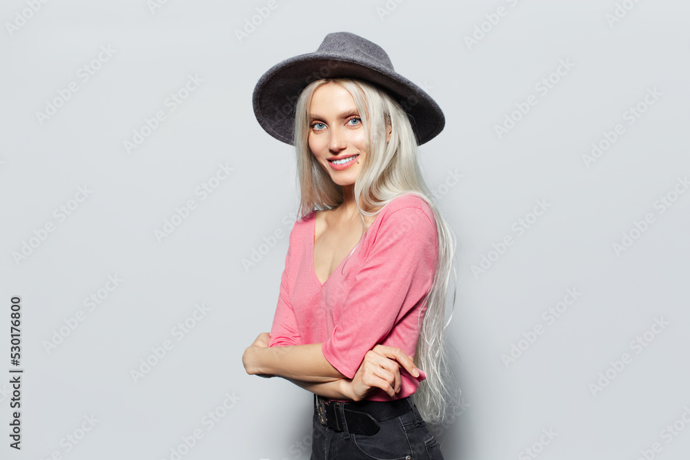 Studio portrait of happiness young blonde pretty girl in pink shirt wearing grey hat on white background. Studio portrait of happiness young blonde pretty girl in pink shirt wearing grey hat on white background.