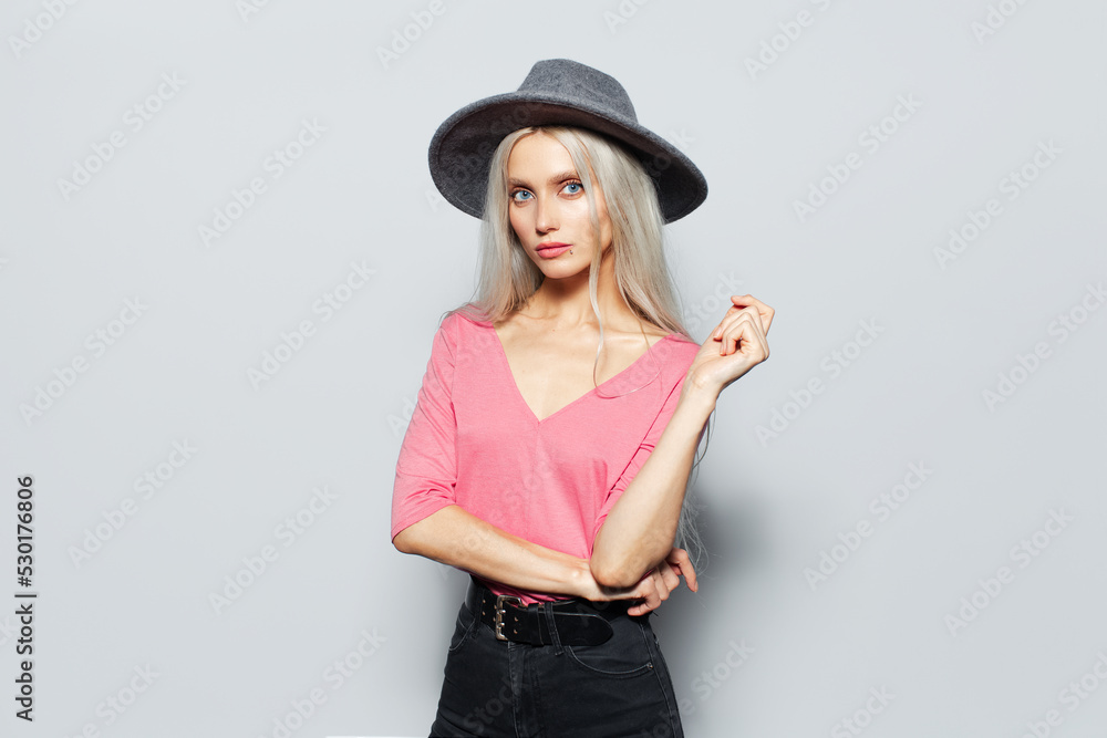 Studio portrait of young blonde cute girl in pink shirt wearing grey hat on white background. Studio portrait of young blonde cute girl in pink shirt wearing grey hat on white background.