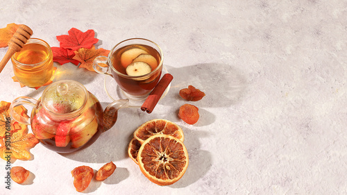 Autumn banner with hot fruit tea in a glass cup, honey and spices on the background of seasonal flowers and leaves, cozy warm concept, hello autumn, hygge style, selective focus, top view, 