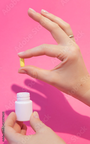 A hand takes out pills for the treatment of an illness from a jar.