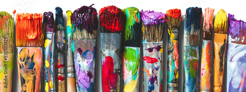 Row of artist paintbrushes closeup. Artistic brushes smeared with paints, isolated. photo