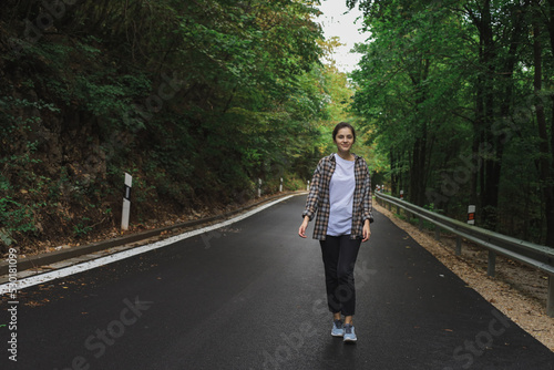 beautiful girl walks in the forest near the road