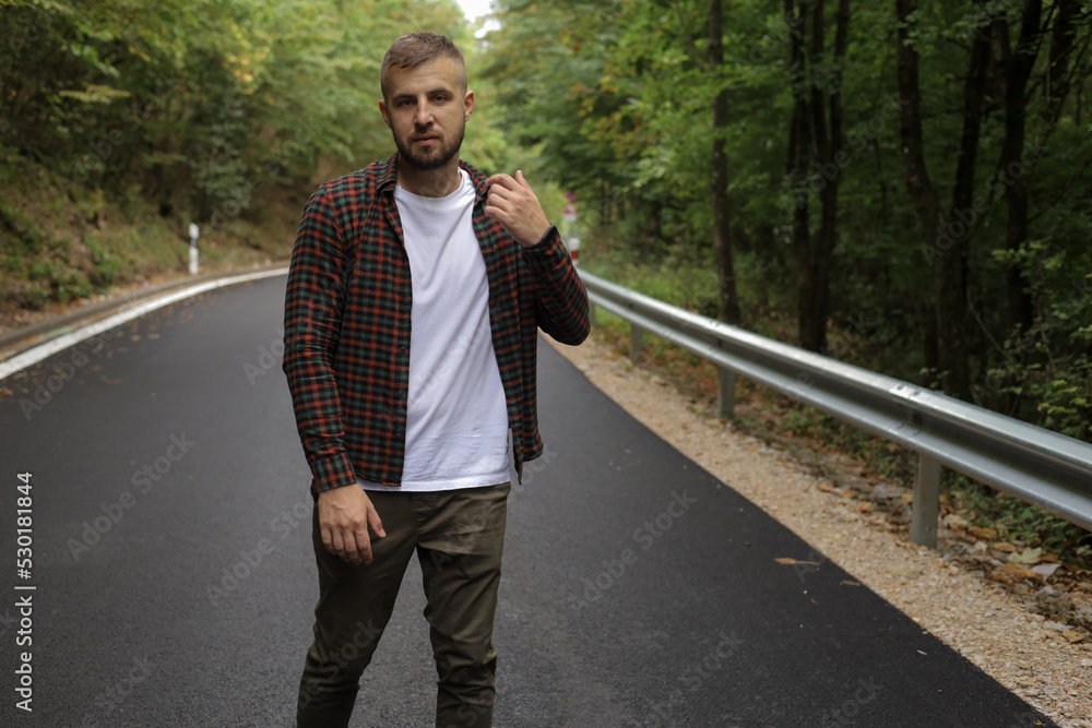 a young man is walking near the road and in the forest a young man is walking near the road and in the forest