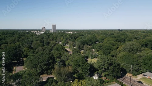 Drone flying around suburb neighborhoods with city skyscrapers in the background.