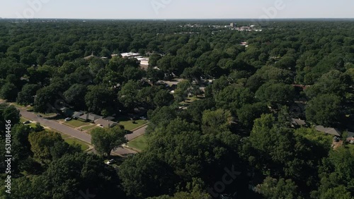 Drone flying around suburb neighborhoods with city skyscrapers in the background.