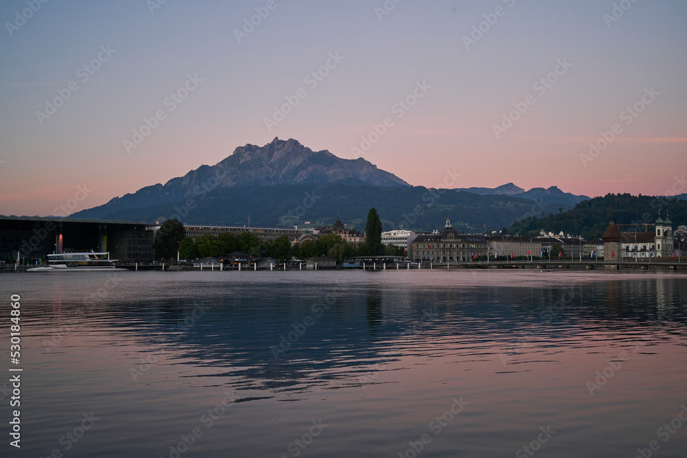 City near sea against mountains at sunset