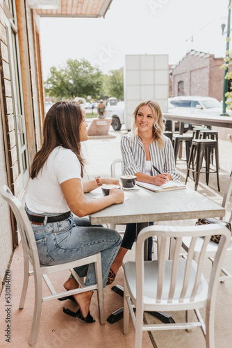 Two young professional females laugh together during meeting