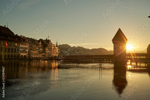 Old tower and bridge crossing river under sundown sky in Switzerland