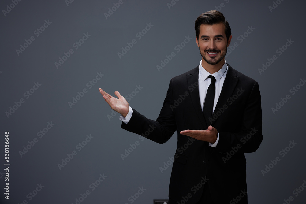 Man businessman smiling happily with his teeth raised hands up in a business suit with tie on a dark gray background Man businessman smiling happily with his teeth raised hands up in a business suit with tie on a dark gray background