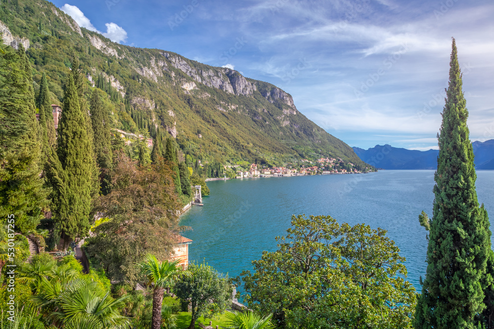 Fototapeta premium Idyllic Lake Como coastline with village and cypresses at sunny day, Italy