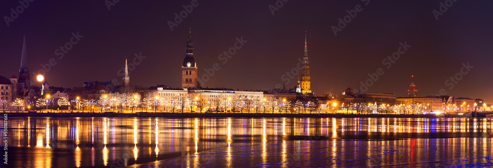 Wide cityscape panorama of Old Riga in night time with rich illumination.