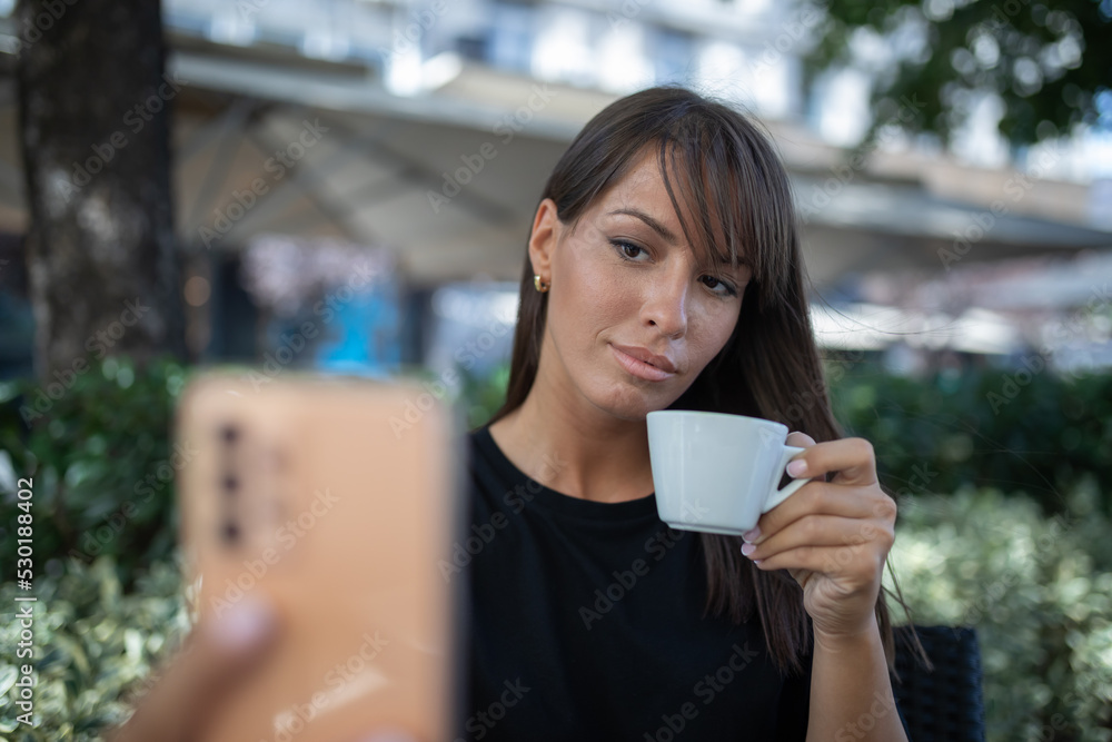 Morning in cafe - attractive woman in black drinkin coffe and make selfie photo for social networks Morning in cafe - attractive woman in black drinkin coffe and make selfie photo for social networks