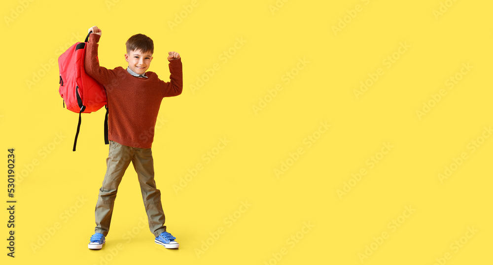 Fototapeta premium Little schoolboy holding backpack on yellow background with space for text