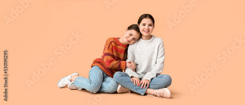 Cute twin girls on beige ba...